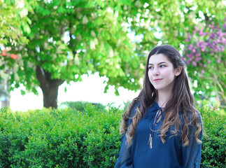 Fototapeta premium portrait of a beautiful girl with dark hair and blue eyes against the background of flowering trees, spring