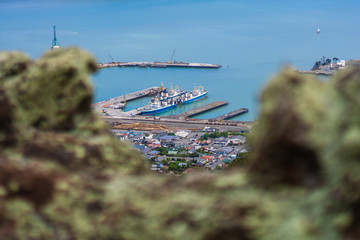 Framed by green rock, port in distance surrounded by blue bay