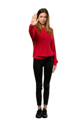 A full-length shot of a Young woman with red sweater making stop gesture denying a situation that...