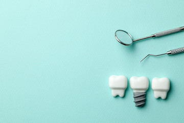 Healthy white teeth and implants  on green mint background and dentist tools mirror, hook. Copy space for text.