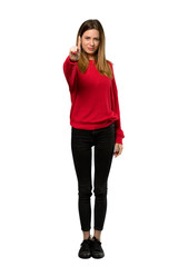 A full-length shot of a Young woman with red sweater showing and lifting a finger over isolated white background
