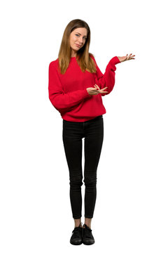 A full-length shot of a Young woman with red sweater extending hands to the side for inviting to come over isolated white background