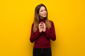Fototapeta premium Woman with turtleneck over yellow wall scheming something