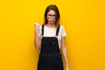 Woman over yellow wall with angry gesture