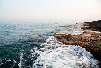 Aerial top view of sea waves hitting rocks on the beach with turquoise sea water. Amazing rock cliff seascape in the coastline. Aerial view of sea waves and fantastic Rocky coast. Mediterranean Sea.