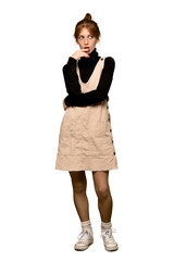 A full-length shot of a Young redhead woman having doubts while looking up over isolated white background