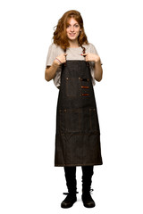 A full-length shot of a Young redhead woman with apron with surprise facial expression over isolated white background