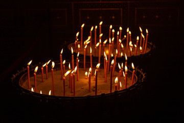 Candles lit in a stand with sand in a church in Prague