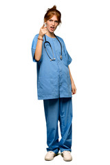 A full-length shot of a Young redhead nurse frustrated by a bad situation and pointing to the front over isolated white background