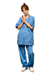 A full-length shot of a Young redhead nurse scheming something over isolated white background