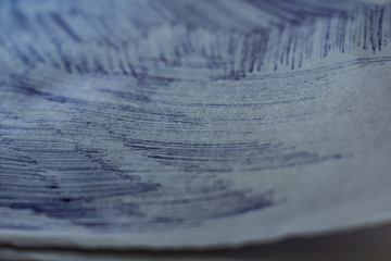A sheet of white paper with painted dirty strokes, a blue ballpoint pen. Blurred background, shallow depth of field. Drawn record. Incomprehensible scribbles. The texture of an ordinary sheet of torn 