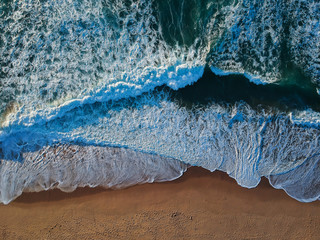 Aerial view of sandy beach with waves and clear ocean water. Drone phot