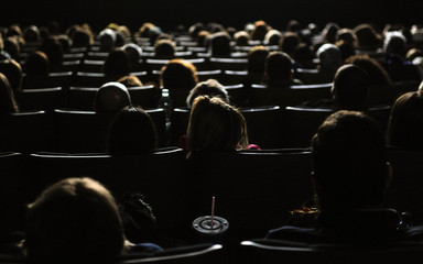 People in the cinema watching a movie, illuminated by the big screen
