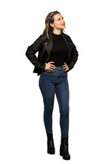 Fototapeta premium A full-length shot of a Teenager girl with leather jacket posing with arms at hip and laughing on isolated white background