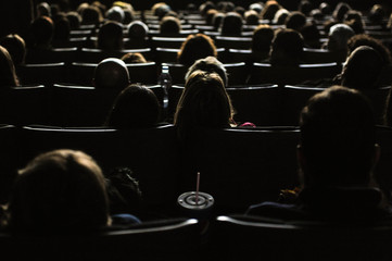 People in the cinema watching a movie, illuminated by the big screen
