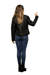 A full-length shot of a Teenager girl with leather jacket pointing back with the index finger on...