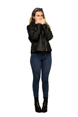 A full-length shot of a Teenager girl with leather jacket is a little bit nervous and scared putting hands to mouth on isolated white background