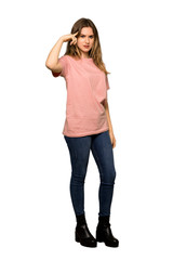 A full-length shot of a Teenager girl with pink sweater making the gesture of madness putting finger on the head on isolated white background