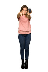 A full-length shot of a Teenager girl with pink sweater with a broken phone on isolated white background