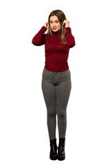 Fototapeta premium A full-length shot of a Teenager girl with turtleneck frustrated and covering ears with hands over isolated white background