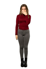 A full-length shot of a Teenager girl with turtleneck covering mouth with hands for saying something inappropriate over isolated white background