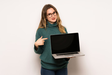 Naklejka premium Teenager girl over white wall showing a laptop