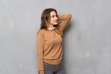Fototapeta premium Teenager girl over textured wall thinking an idea while scratching head