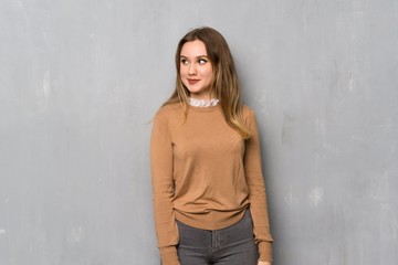 Teenager girl over textured wall looking to the side