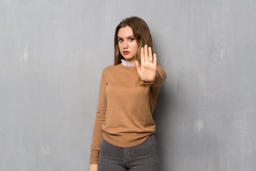 Teenager girl over textured wall making stop gesture denying a situation that thinks wrong