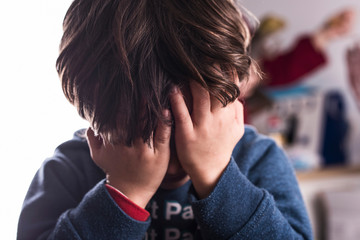 little boy covers his eyes out of fear or embarrassment