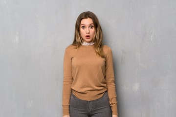 Teenager girl over textured wall surprised and shocked while looking right