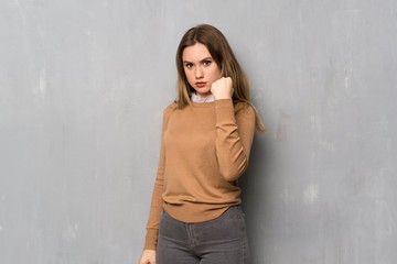 Teenager girl over textured wall with angry gesture