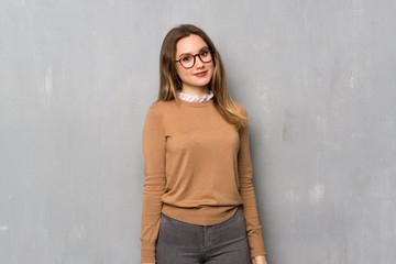 Teenager girl over textured wall with glasses and happy
