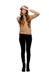 Full-length shot of Young woman with beret with troubled holding broken smartphone on isolated white background