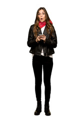 Full-length shot of Young woman with leather jacket surprised and sending a message on isolated white background
