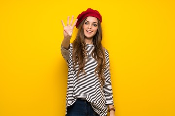 Girl with french style over yellow wall happy and counting four with fingers