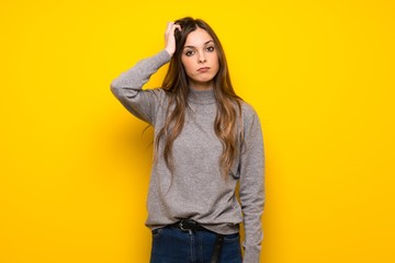 Young woman over yellow wall with an expression of frustration and not understanding