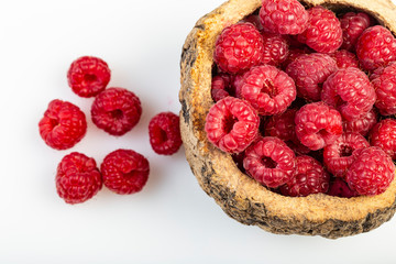 Lamponi in ciotola di legno su sfondo bianco