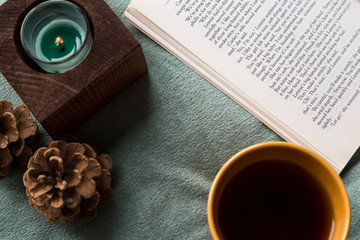 The cup of tea or coffee with a book and candle on the wooden table near the window on the rainy...