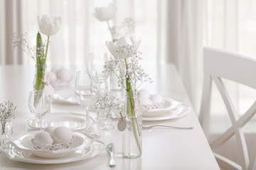 Happy Easter! Decor and table setting of the Easter table with white tulips and dishes of white color.