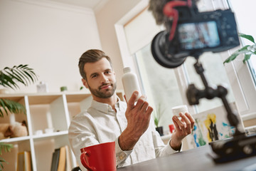 Good choice. Portrait of positive and young male blogger recording video blog episode about new cosmetic products.