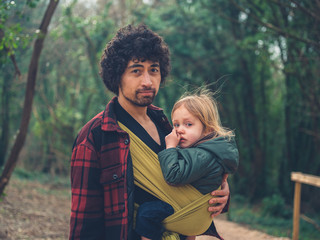Father with toddler in sling exploring forest
