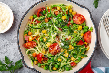 zucchini noodle with tomato, corn and green peas on pan, healthy vegan food