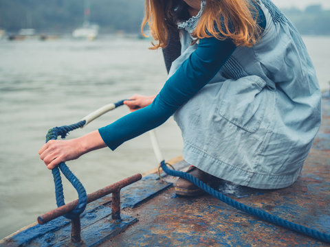 Young woman tying rope on jetty