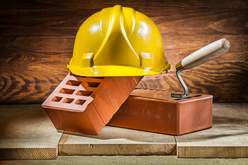 bricks trowel and helmet on vintage wood