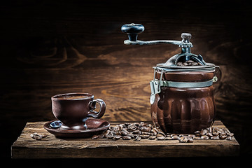 vintage clay coffee mill and cup with beans on wood board