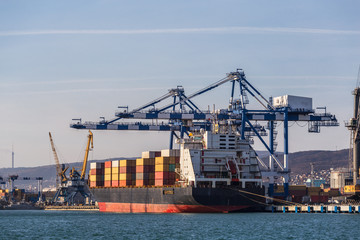 Containers on freight ship in industrial sea port for shipping and logistic, cranes and other...