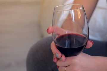 Woman with a glass of red wine in her hands, hands close-up.