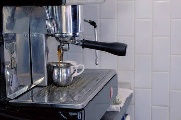 Pouring espresso to pitcher from coffee machine.