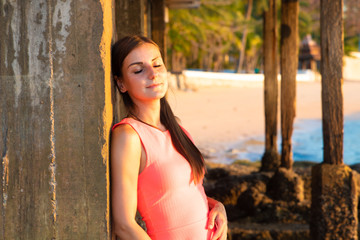Fototapeta premium A woman stands on the beach in the evening. The girl at sunset. Attractive young lady enjoying the last rays of the sun. copy space place for text